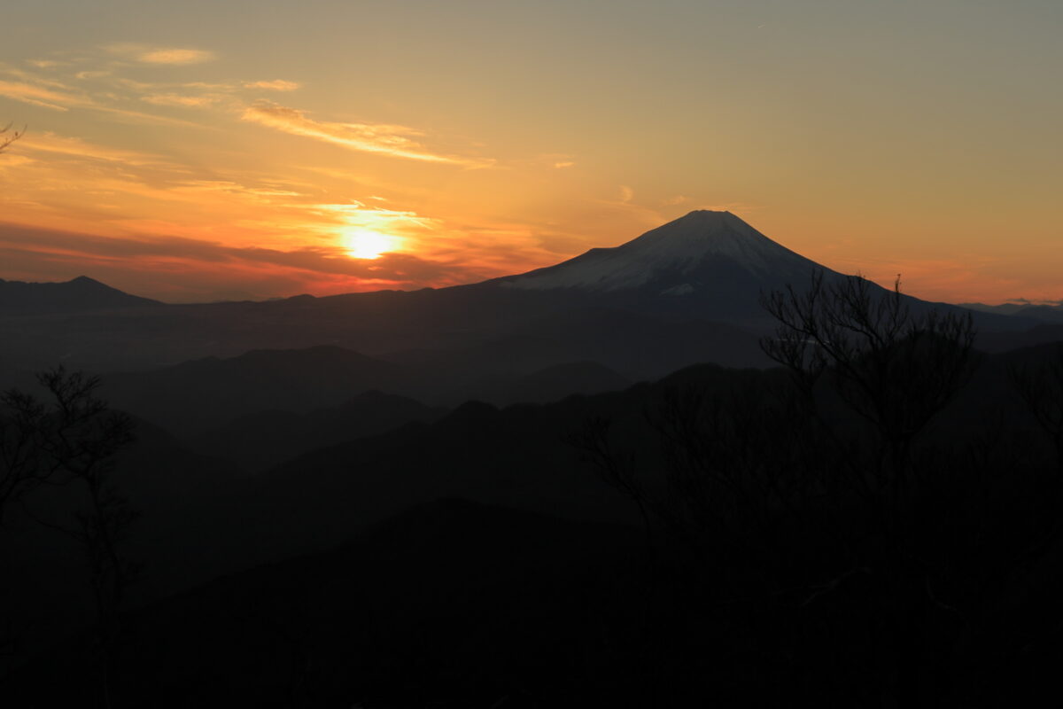 丹沢山山頂から眺める富士山の横に沈んでいく夕陽
